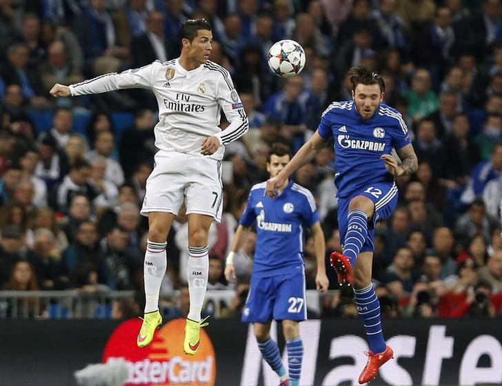 © Reuters. Real Madrid's Cristiano Ronaldo is challenged by Schalke 04's Marco Hoger during their round of 16 second leg soccer match in Madrid