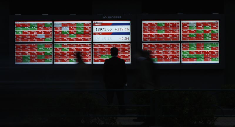 © Reuters. Man looks at an electronic board showing Japan's Nikkei average outside a brokerage in Tokyo