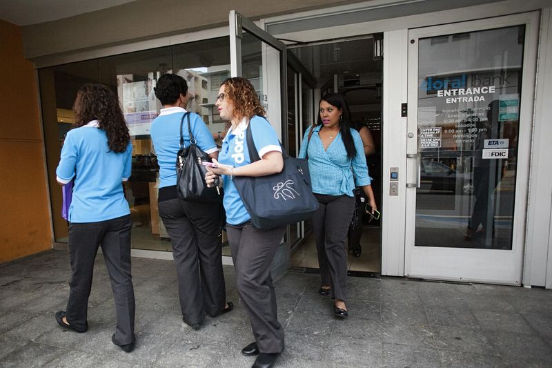 © Reuters. Employees of the Doral Bank leave a branch of the bank after it was closed in San Juan