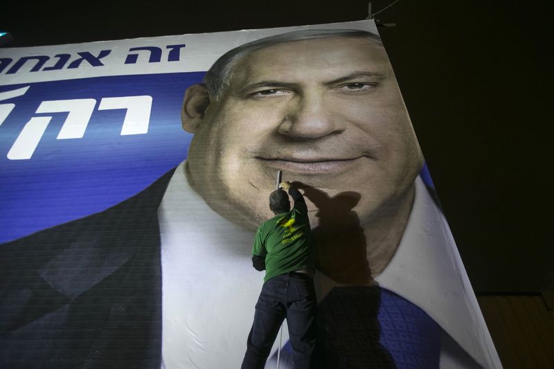 © Reuters. Homem instala outdoor de campanha do premiê de Israel, Benjamin Netanyahum em Tel Aviv