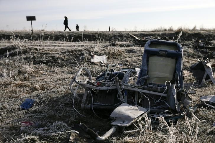 © Reuters. Men walk past wreckage of MH17, Malaysia Airlines Boeing 777 plane, at site of plane crash near village of Hrabove in Donetsk region