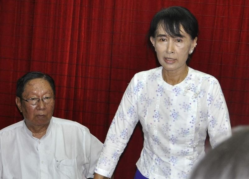 © Reuters. Myanmar pro-democracy leader Aung San Suu Kyi talks to reporters with Spokesman of the National League for Democracy (NLD), Nyan Win, at the Democracy Party head office in Yangon