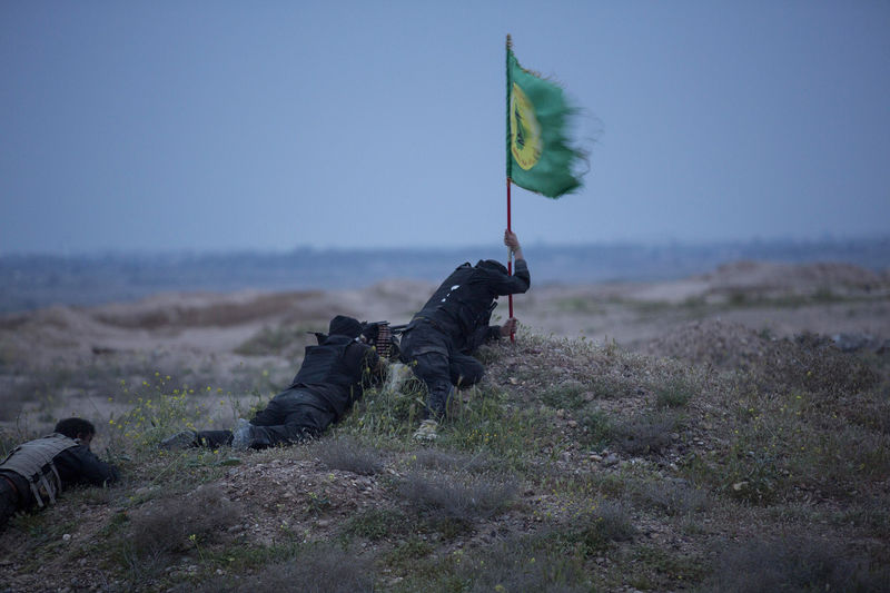 © Reuters. Shi'ite fighters, known as Hashid Shaabi, clash with Islamic State militants, as one tries to put a Shi'ite flag in the ground, in northern Tikrit