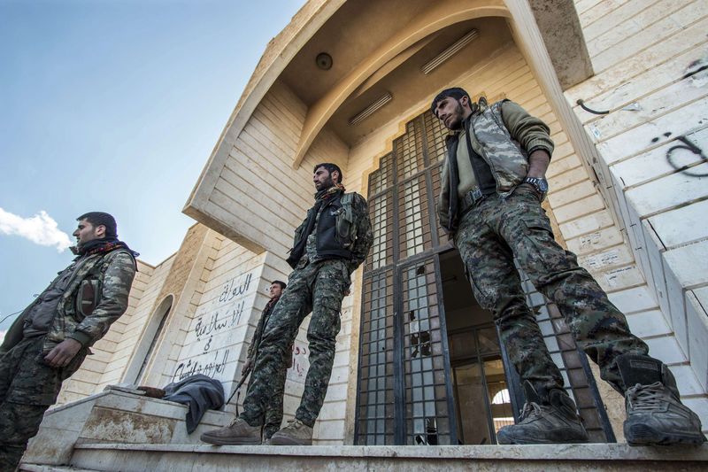 © Reuters. Kurdish People's Protection Units (YPG) fighters stand outside one of the Islamic State headquarters in Tel Hamis in northeast Syria, after the YPG took control of the area