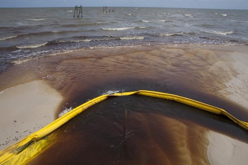 © Reuters. A protective boom is seen as oil from the Deepwater Horizon spill recedes back into the Gulf of Mexico after washing into a drainage canal in Waveland