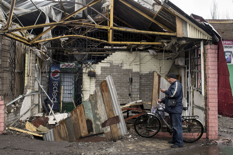 © Reuters. A man checks his mobile phone in front of his destroyed house in the town of Debaltseve, north-east from Donetsk