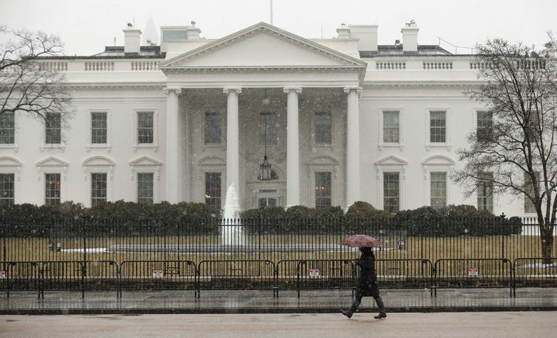 © Reuters. Snow starts to fall as a woman walks past the White House in Washington