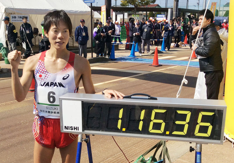 © Reuters. Japan's Yusuke Suzuki poses next to a electric time board showing his record after breaking the 20-kilometer race walk world record at the IAAF Race Walking Challenge, in Nomi