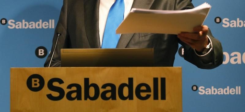 © Reuters. Banc Sabadell's Chairman Josep Oliu shows a dossier of the company's 2014 results during a news conference at its headquarters in central Barcelona