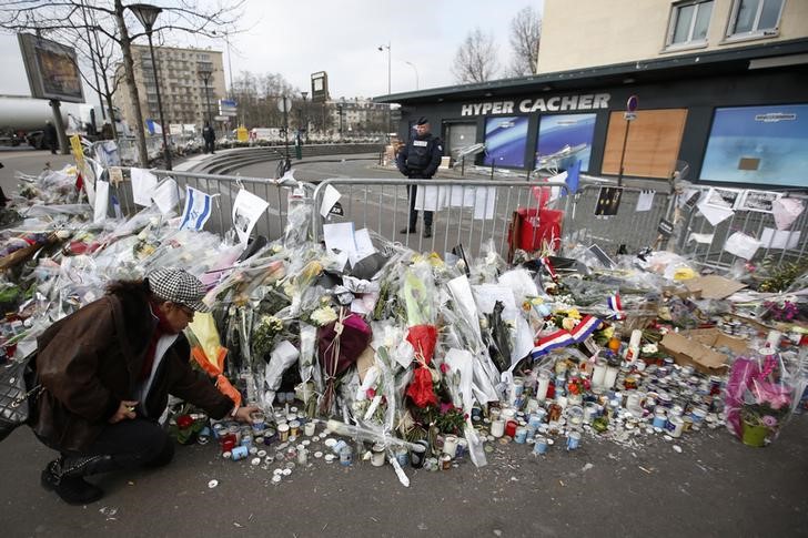 © Reuters. A woman lights candles in front of the Hyper Cacher kosher supermarket at the Porte de Vincennes