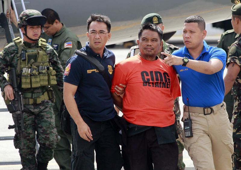 © Reuters. Members of the Philippine National Police intelligence escort Mohammad Ali Tambako, founder and leader of the Justice Islamic Movement, upon arrival at Villamor Air Base in Manila