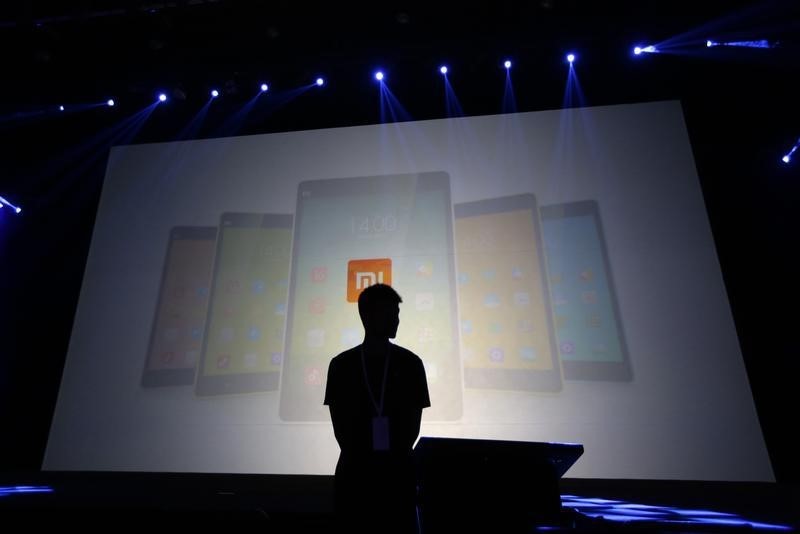 © Reuters. Security guard stands in front of a screen showing Xiaomi mobile phones ahead of the launching ceremony of Xiaomi Phone 4, in Beijing