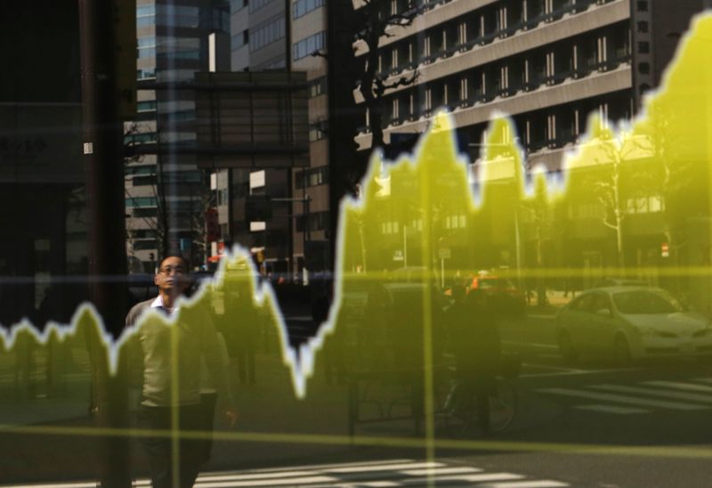 © Reuters. A pedestrian is reflected in an electronic board showing the graph of the recent fluctuations of Japan's Nikkei average outside a brokerage in Tokyo