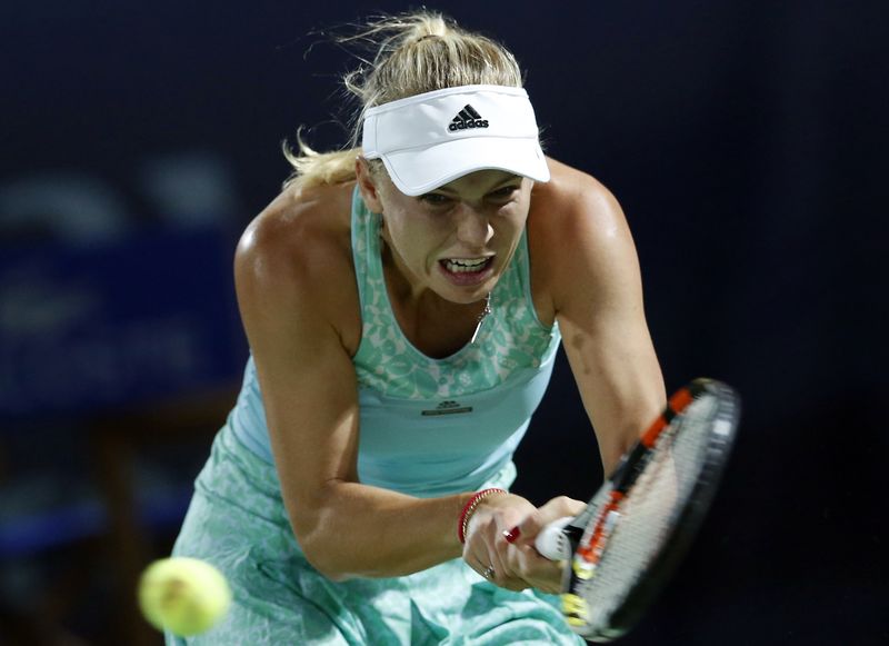 © Reuters. Caroline Wozniacki of Denmark returns the ball to Simona Halep of Romania during their women's singles tennis semi-final match at the WTA Dubai Tennis Championships