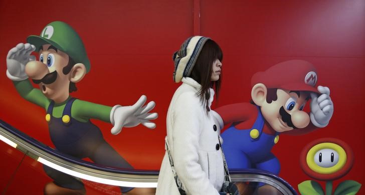 © Reuters. A shopper rides an escalator past Nintendo ads at an electronics retail store in Tokyo