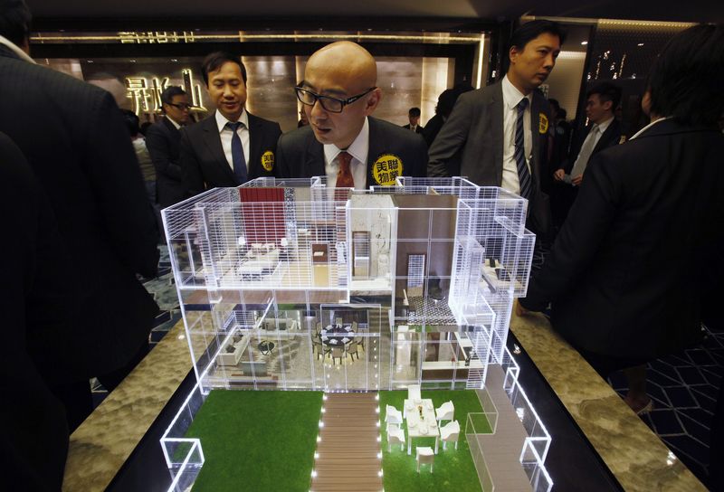 © Reuters. File photo of a property sales agent looking at a penthouse unit model at a promotional event in Hong Kong