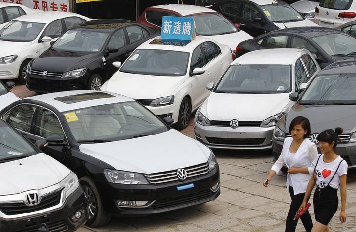 © Reuters. Women walk past Volkswagen and Honda cars on display at an automobile market in Beijing