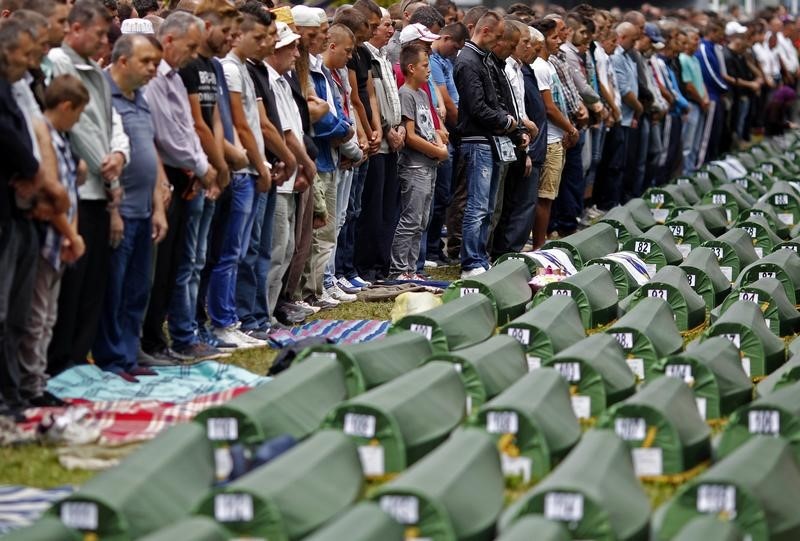 © Reuters. Bosnian Muslims pray during a mass funeral for newly identified victims from the Srebrenica massacre, at Potocari Memorial Center, near Srebrenica
