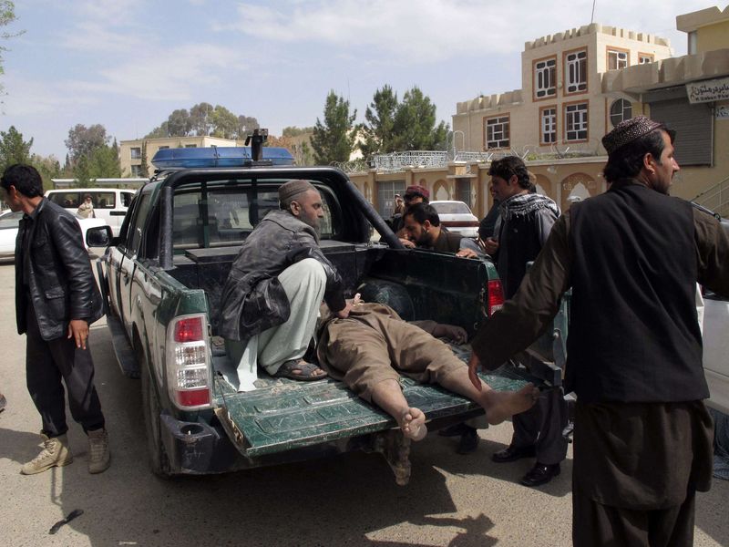 © Reuters. Men transport the victim of a suicide attack from the scene in Lashkar Gah, Helmand province