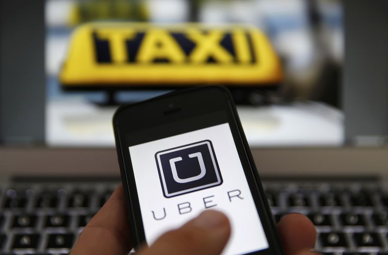 © Reuters. File illustration picture shows the logo of car-sharing service app Uber on a smartphone next to the picture of an official German taxi sign