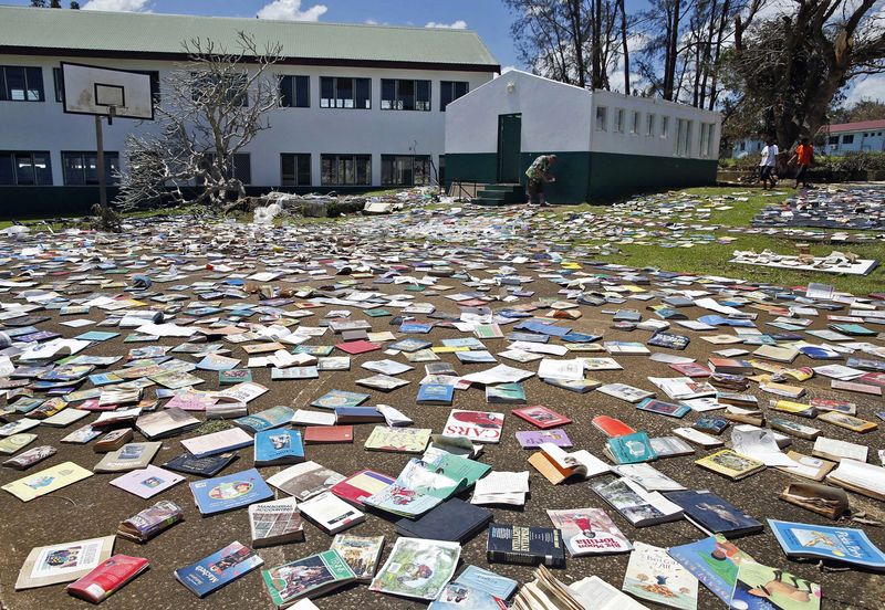 © Reuters. Headmaster Hatyay and teachers of Central School lay out books to dry in the sun after the roof of the school's library was blown away by Cyclone Pam in Port Vila