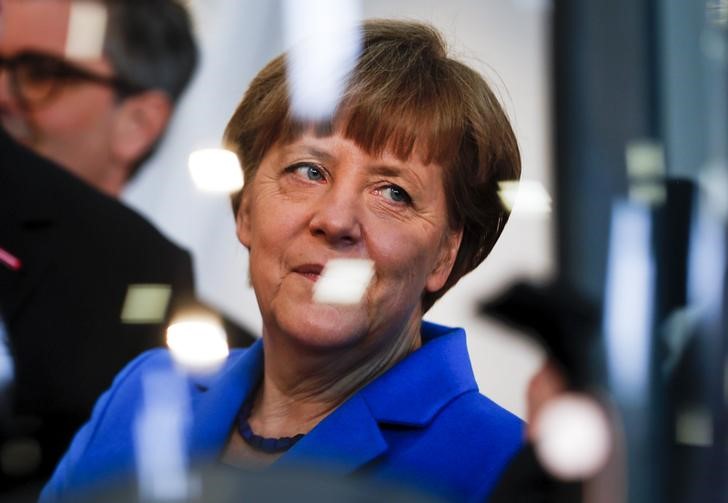 © Reuters. German Chancellor Angela Merkel is seen through a window during her visit at the International Trade Fair in Munich