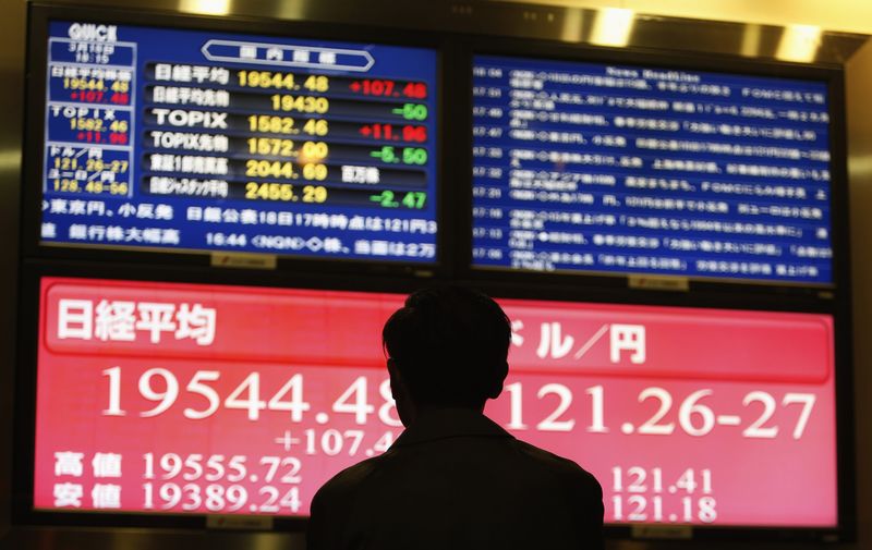 © Reuters. A man looks at a monitor showing the Japan's Nikkei average and the exchange rates between the Japanese yen and the U.S. dollar in Tokyo