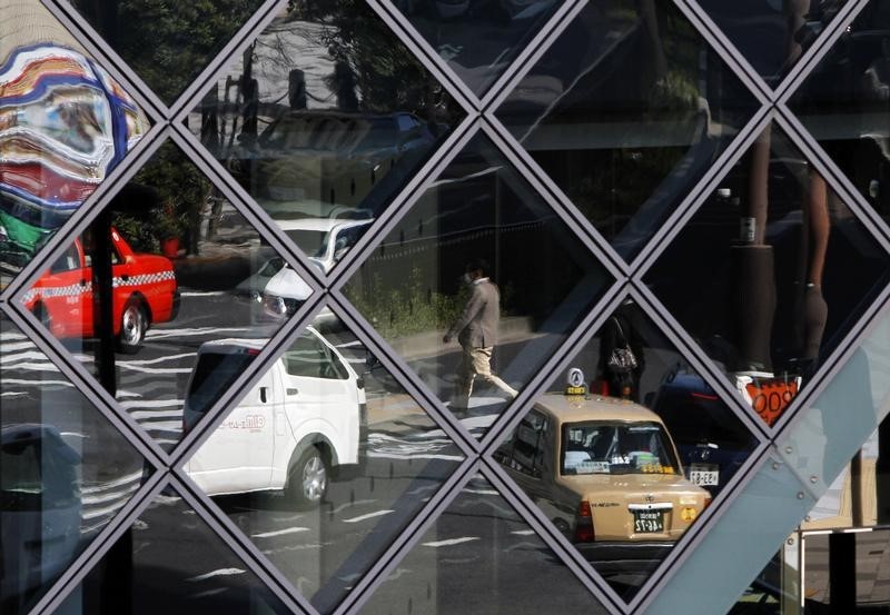 © Reuters. Man and cars are reflected on windows in Tokyo