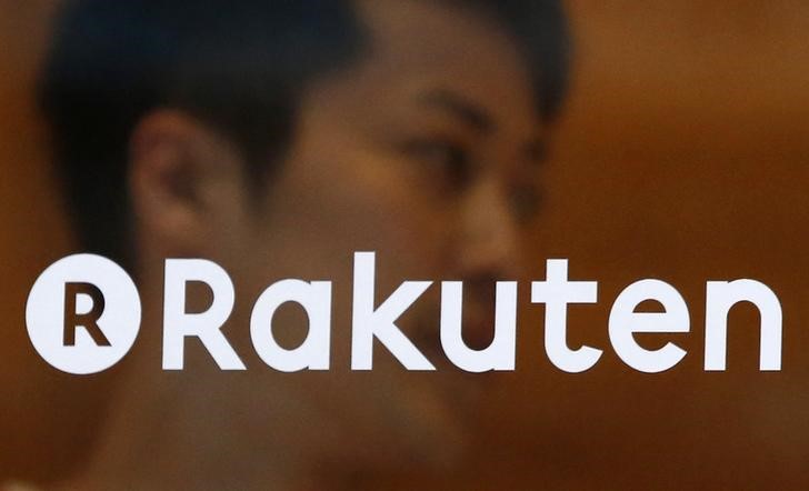 © Reuters. A staff of Rakuten Cafe is seen behind a logo of Rakuten Inc. in Tokyo