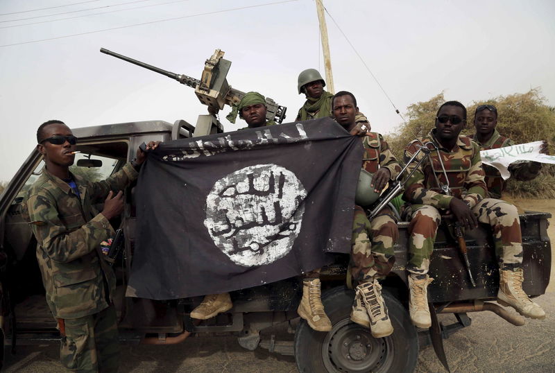 © Reuters. Nigerien soldiers hold up a Boko Haram flag that they had seized in the recently retaken town of Damasak, Nigeria