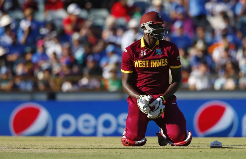 © Reuters. West Indies captain Jason Holder sits up on the pitch after getting home safely following a run out attempt during his Cricket World Cup match against India in Perth