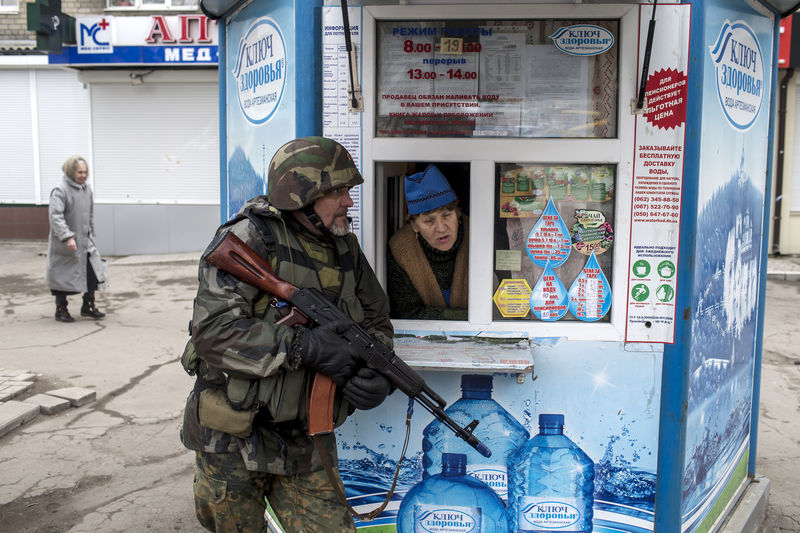 © Reuters. A pro-Russian rebel takes cover as a woman from inside a kiosk looks on, during what the rebels said was an anti-terrorist drill in Donetsk