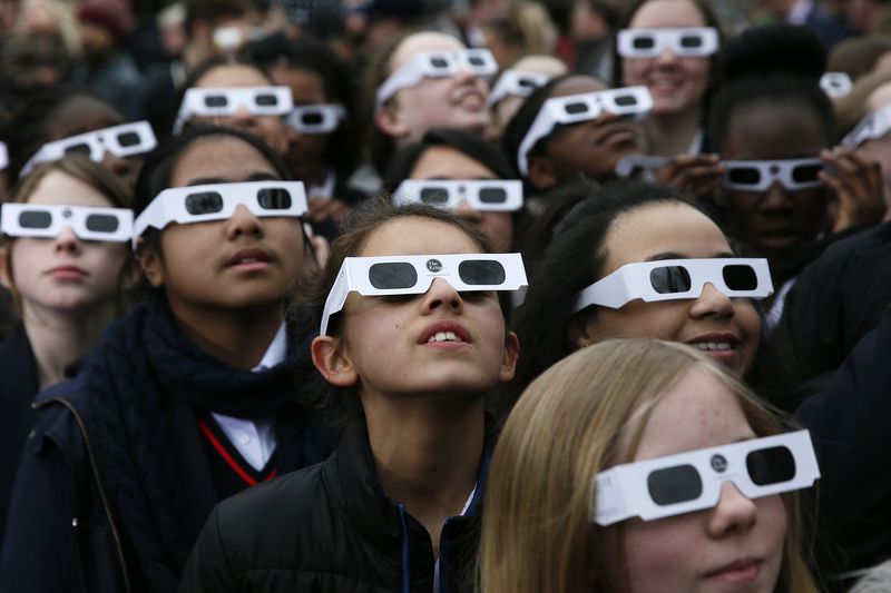 © Reuters. School children wearing protective glasses pose for photographers outside The Royal Observatory during a partial solar eclipse in Greenwich, south east London
