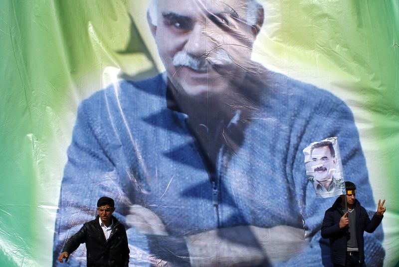 © Reuters. Kurdish men pose for a picture in front of the portrait of jailed Kurdish militant leader Abdullah Ocalan of the Kurdistan Workers Party (PKK) during a gathering celebrating Newroz in Turkey