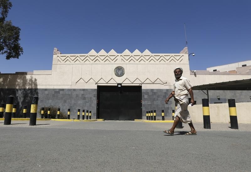 © Reuters. Man walks past the U.S. embassy in Sanaa after the road in front of it was opened by police