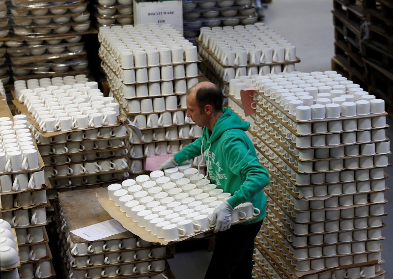 © Reuters. A worker carries cups in the storage facility at the Portmeirion Factory in Stoke-on-Trent