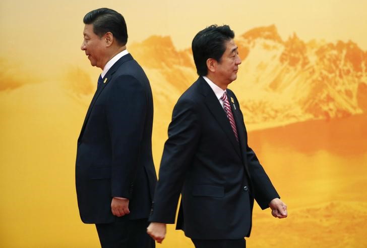 © Reuters. Japan's PM  Abe walks past China's President Xi during welcoming ceremony of APEC forum in Beijing