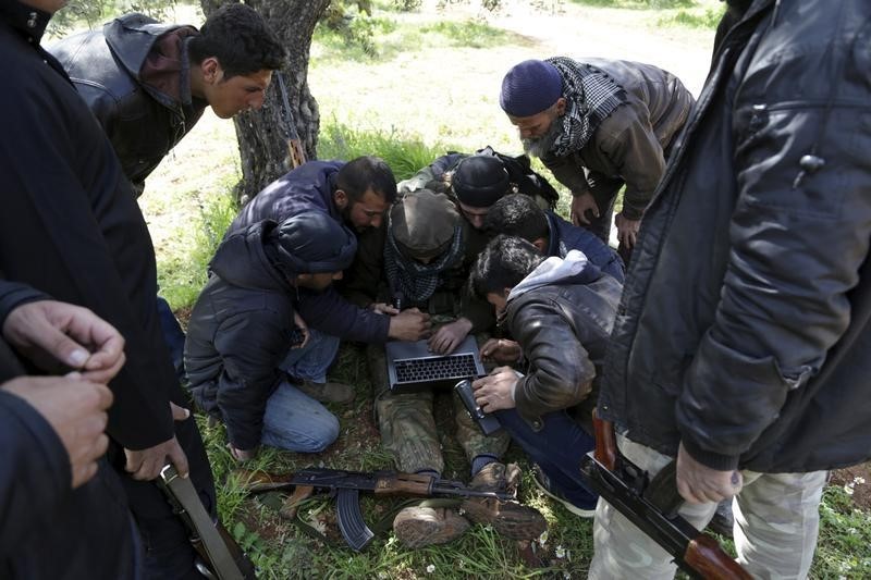 © Reuters. Rebel fighters work on a computer to determine their target points ahead of an offensive against forces loyal to Syria's President Assad at the frontline of Idlib city in northern Syria