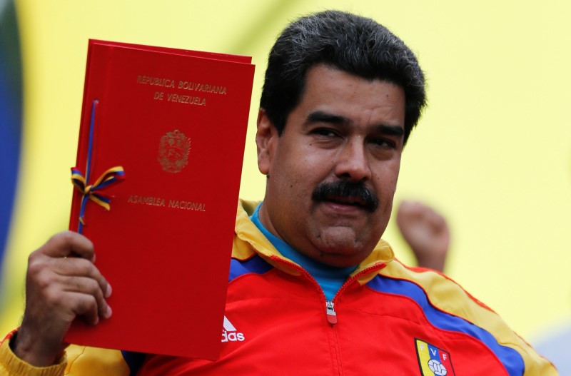 © Reuters. Venezuela's President Nicolas Maduro holds up a law document outside Miraflores Palace in Caracas