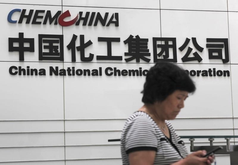 © Reuters. Una donna controlla il telefono di fronte alla sede di China National Chemical Corporation a Pechino