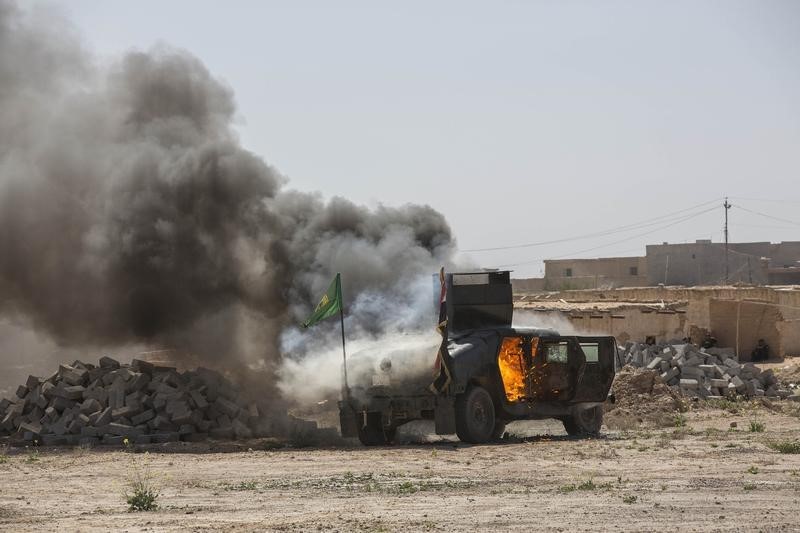 © Reuters. A military vehicle, belonging to Shi'ite fighters known as Hashid Shaabi, burns after being hit by Islamic State militants, during clashes in northern Tikrit