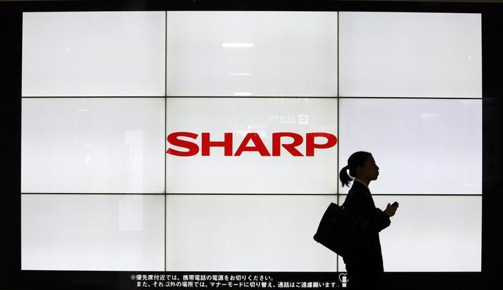 © Reuters. A woman walks past the Sharp Corp's Logo at a train station in Tokyo