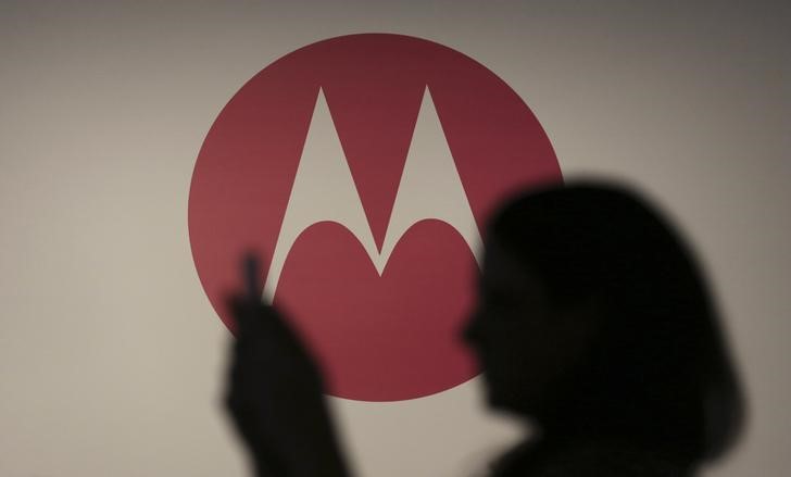 © Reuters. A woman takes a picture in front of a Motorola logo before the worldwide presentation of the Moto G mobile phone in Sao Paulo