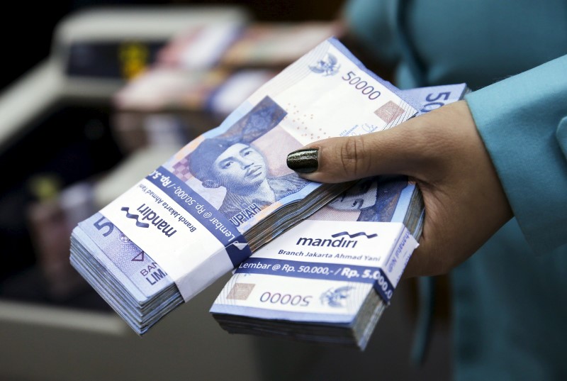 © Reuters. A woman holds Indonesian rupiah notes at money changer in Jakarta