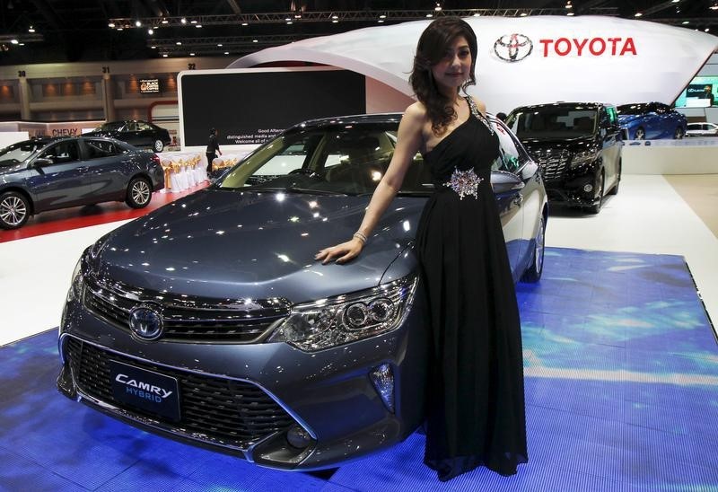 © Reuters. A model poses beside a Toyota Camry Hybrid during a media presentation of the 36th Bangkok International Motor Show in Bangkok 