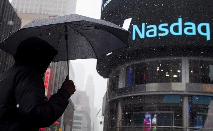 © Reuters. Мужчина с зонтом у здания Nasdaq MarketSite в Нью-Йорке 