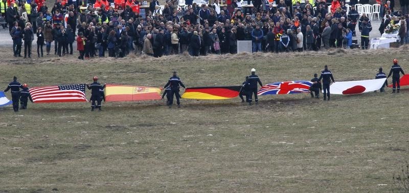 © Reuters.  Flags representing some of the nationalities of the victims are seen as family members and relatives gather near the crash site of an Airbus A320 in the French Alps