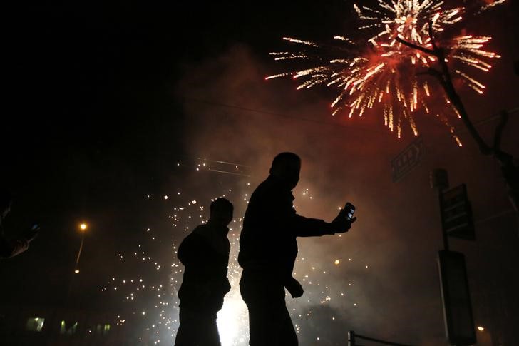 © Reuters. A man tries to take a pictures with his mobile phone as residents set off fireworks as part of Chinese New Year celebrations in Shanghai