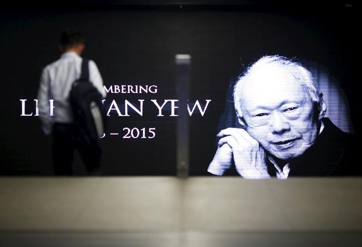 © Reuters. A commuter passes by a signboard bearing an image of the late first prime minister Lee Kuan Yew in a train station at the central business district in Singapore