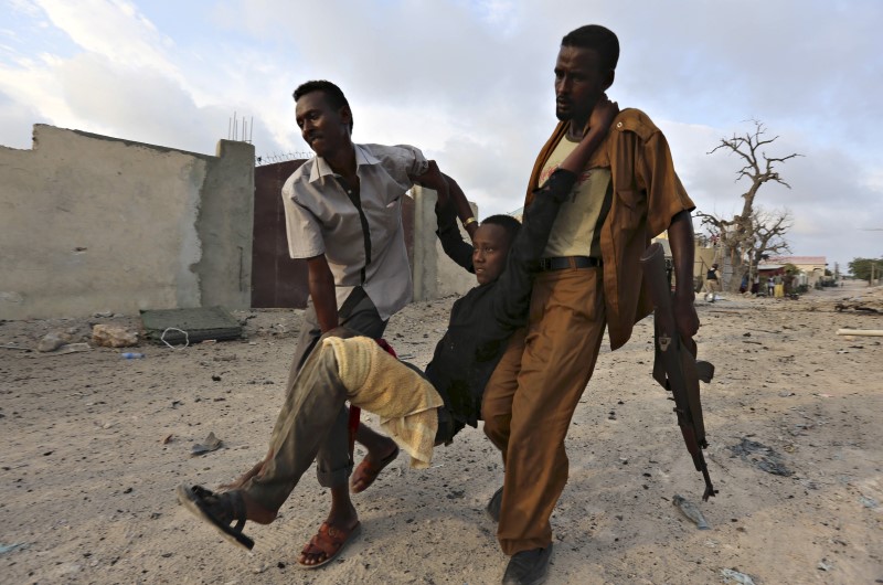 © Reuters. Residents evacuate an injured boy after Islamist group al Shabaab attacked Maka Al-Mukarama hotel in Mogadishu